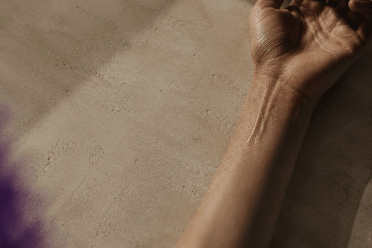 An AURĒ extrait de parfum bottle on a warm neutral surface in natural light